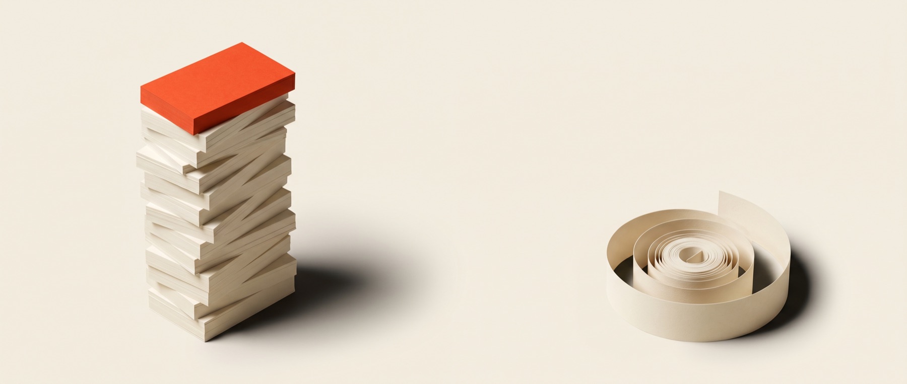 A tall papercraft tower of stacked blocks beside a small tight spiral of rolled paper