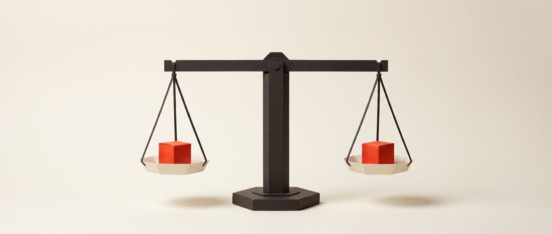 A papercraft balance scale, perfectly level, an identical vermilion cube in each pan