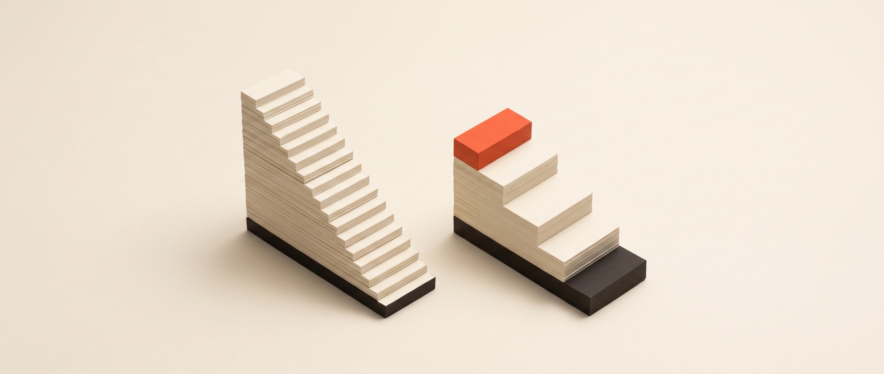Two papercraft staircases side by side, one taller with more steps than the other